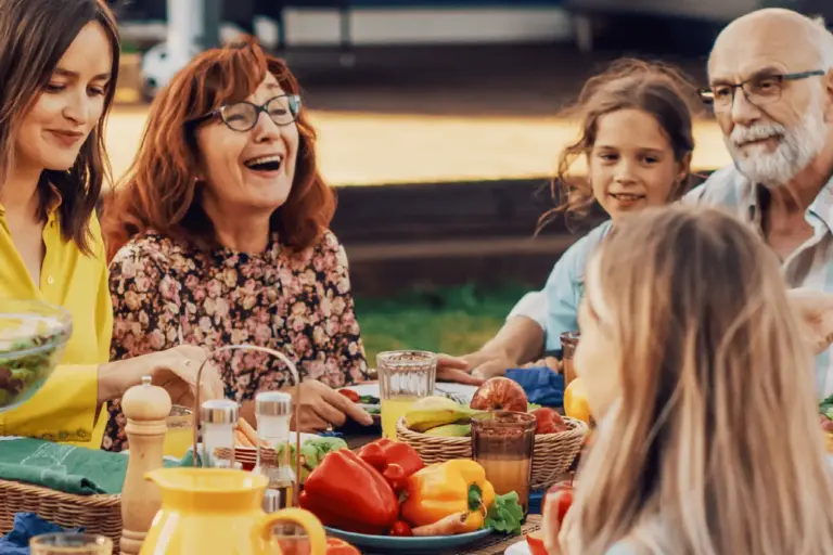 Grandparents enjoy a summer dinner outside with their grandchildren.