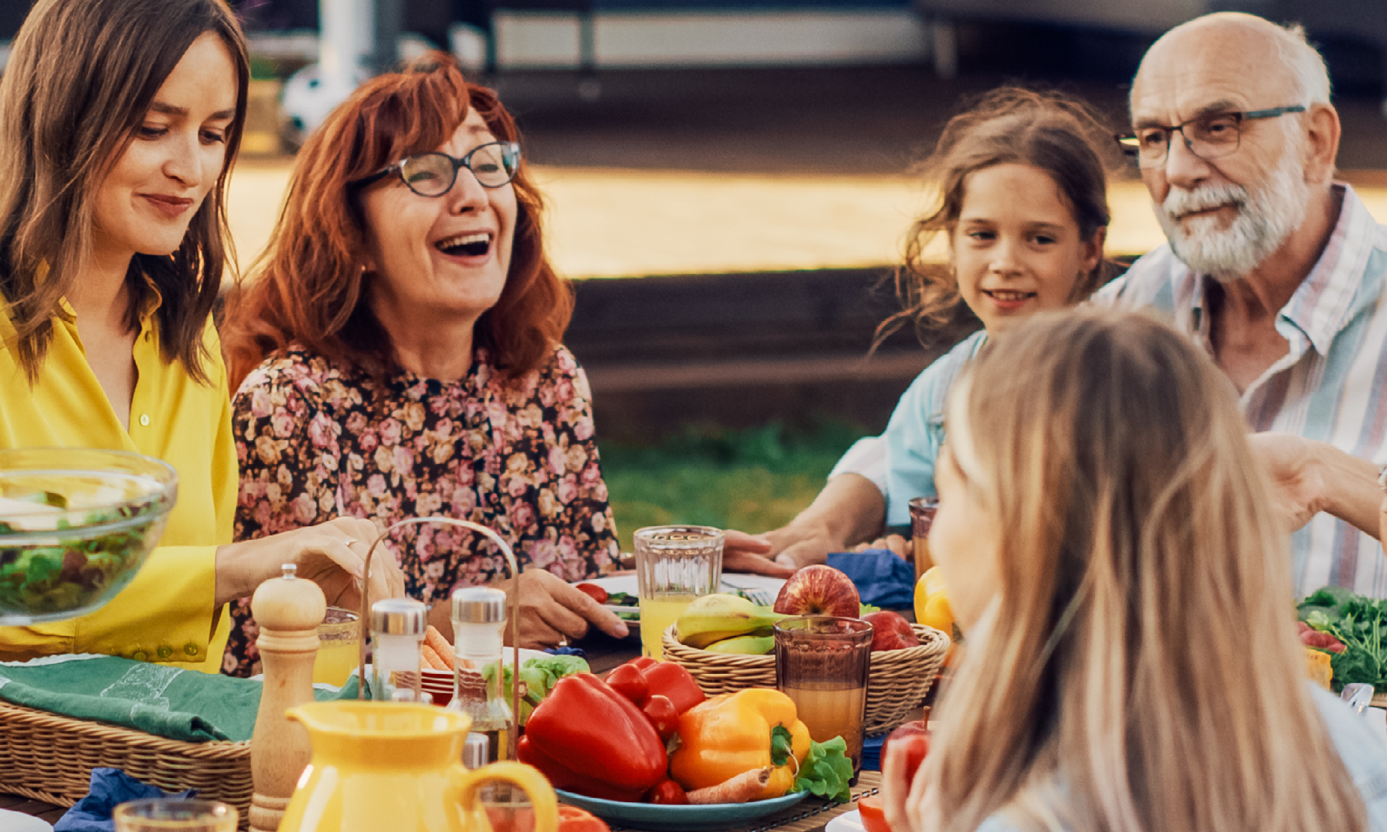 Grandparents enjoy a summer dinner outside with their grandchildren.