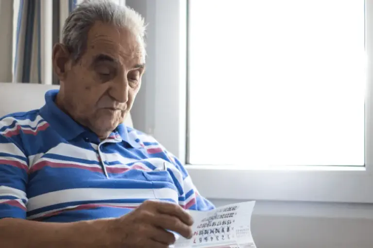 An older gentleman living with mild cognitive memory impairment flips through a calendar.