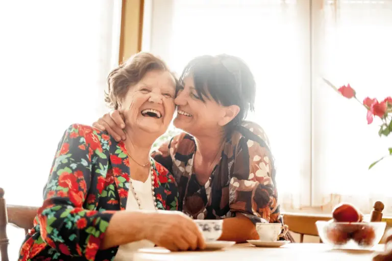 Adult daughter smiles at the dinner table with her mother.