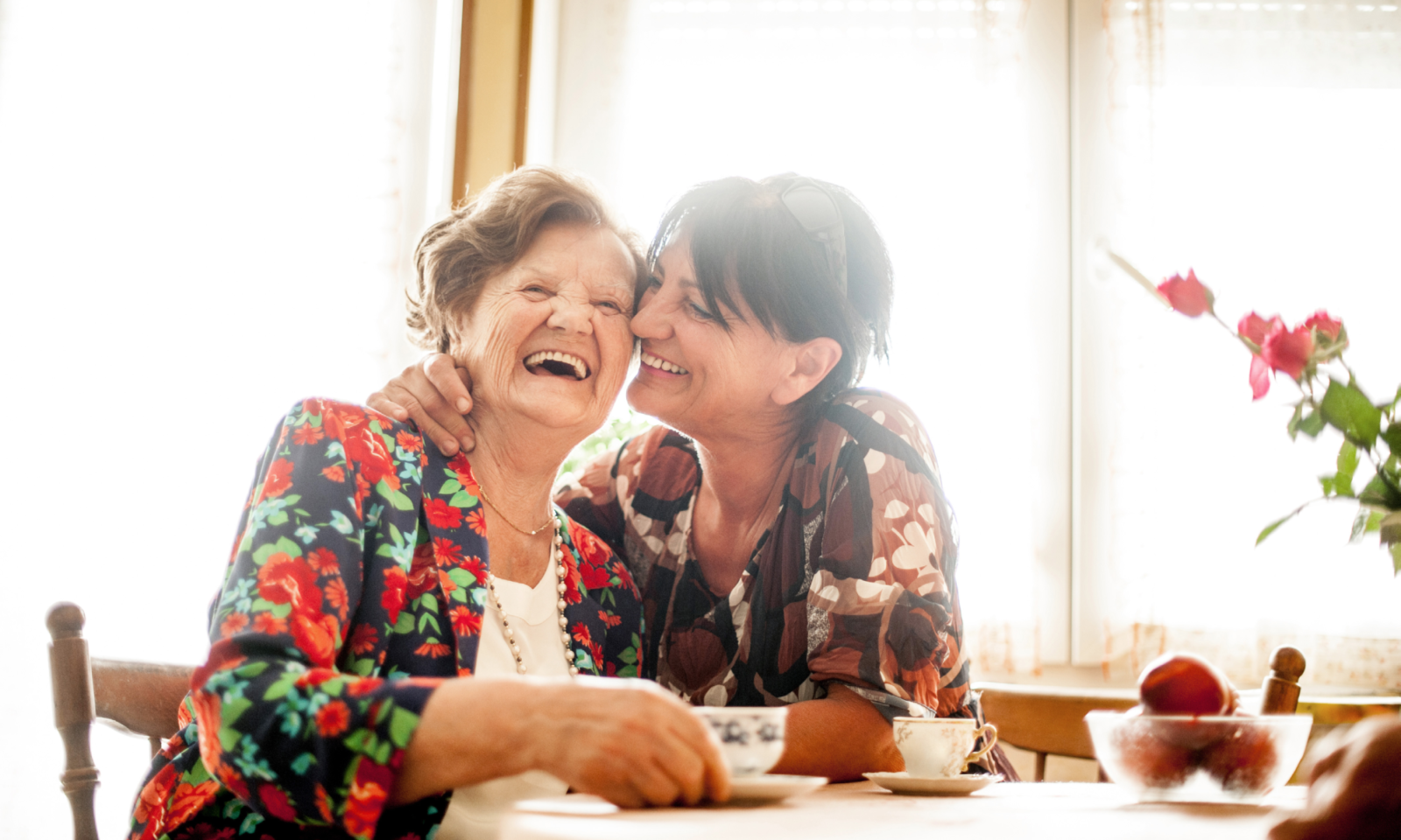 Adult daughter smiles at the dinner table with her mother.