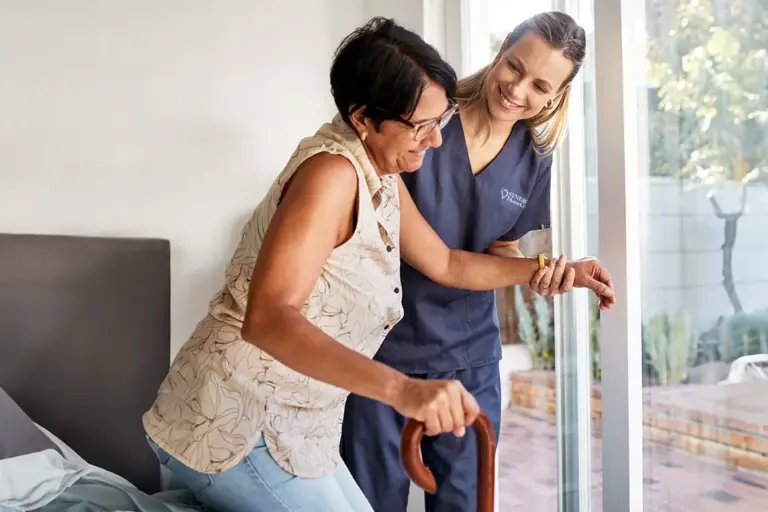 A caregiver helps a client get up and walk