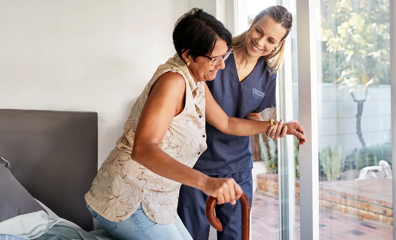 A caregiver helps a client get up and walk