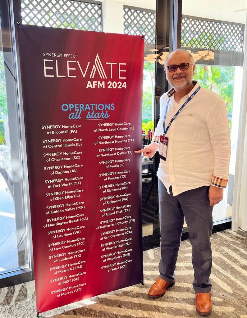 Dr Syed Saad Owner of SYNERGY HomeCare of Northwest Dallas poses with Operations All Stars Award banner.