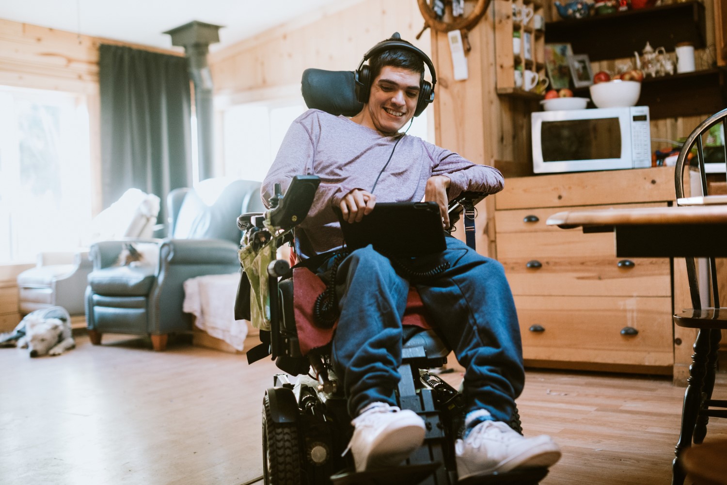 A younger gentleman living with a disability listens to music from a tablet.