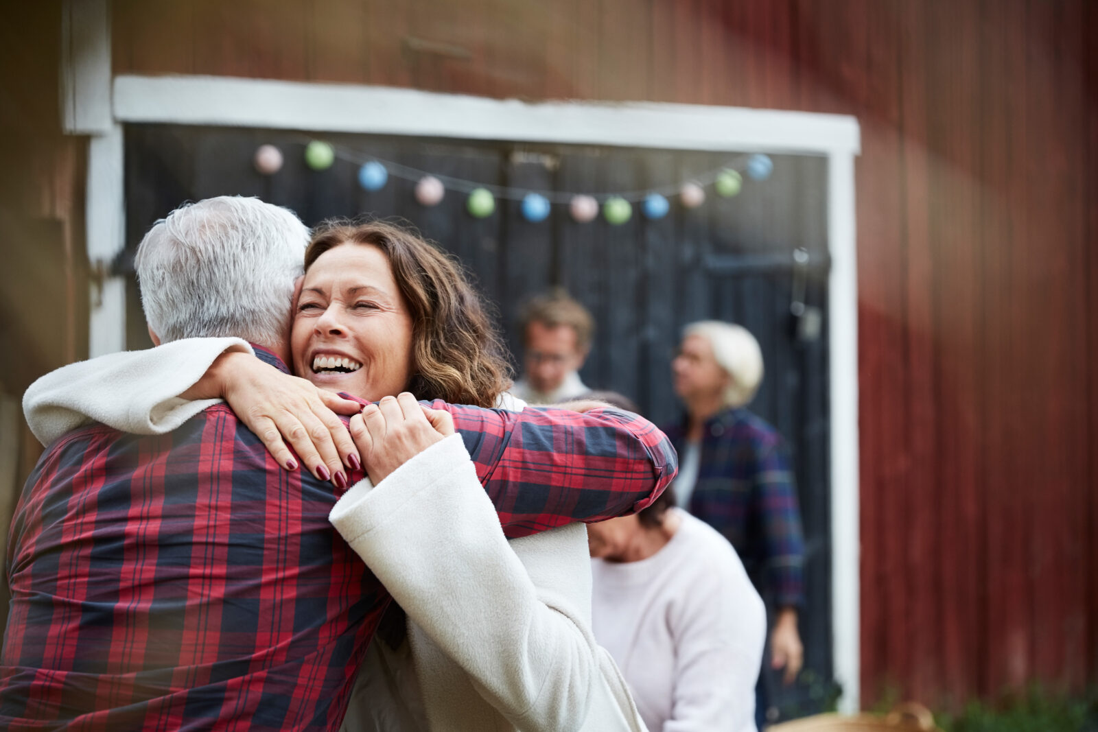 Happy mature woman embracing man while standing at farm