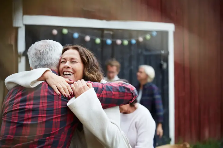 Happy mature woman embracing man while standing at farm