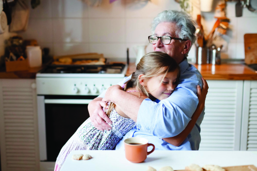 Grandmother hug child girl. Kid and senior woman baking in cozy home kitchen. Happy family
