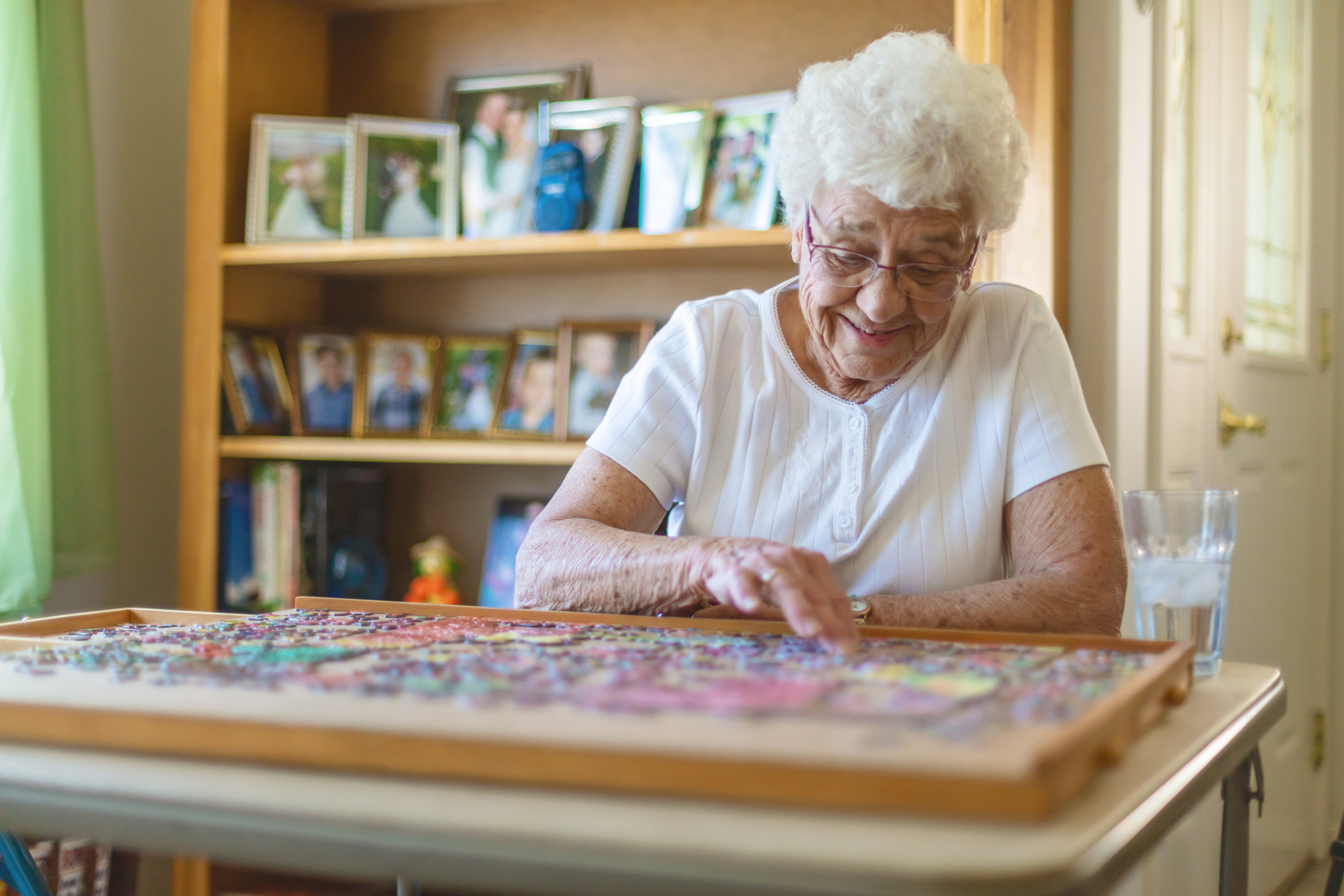 A elderly woman doing a puzzle.