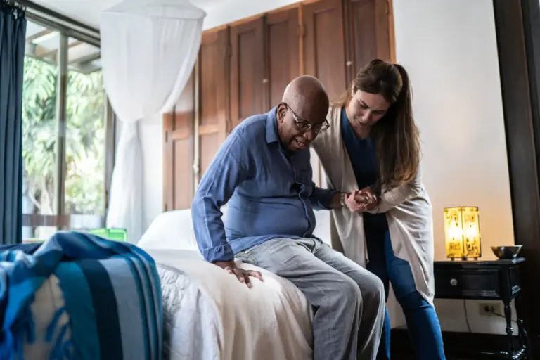 SYNERGY HomeCare caregiver helping a senior man standing up at home