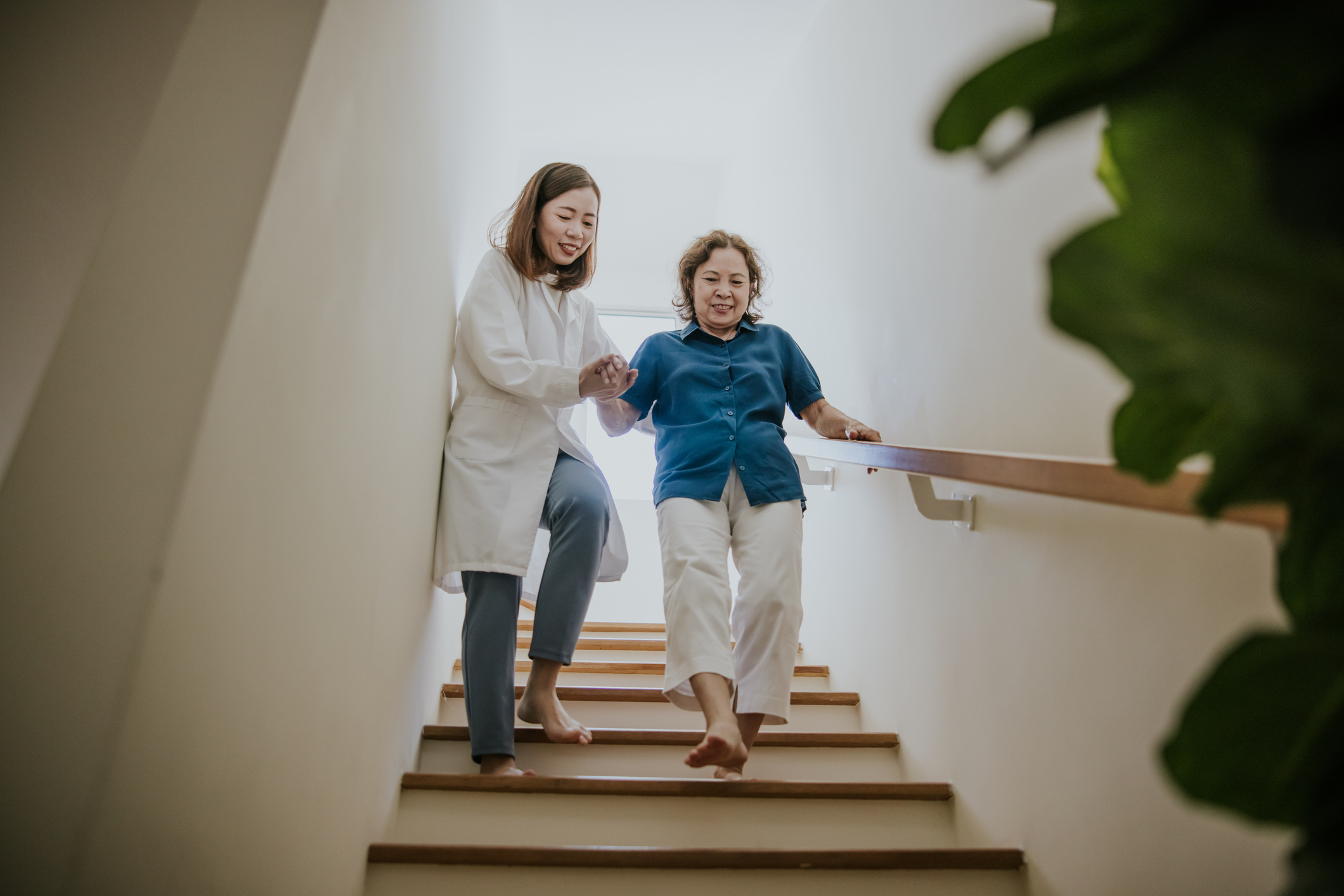 SYNERGY HomeCare senior being helped down the stairs