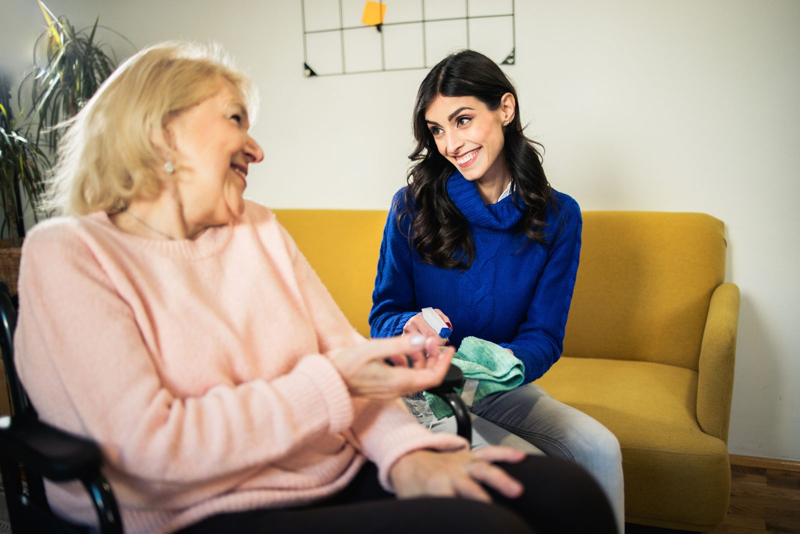 An older woman chats with her granddaughter while she cleans the house.