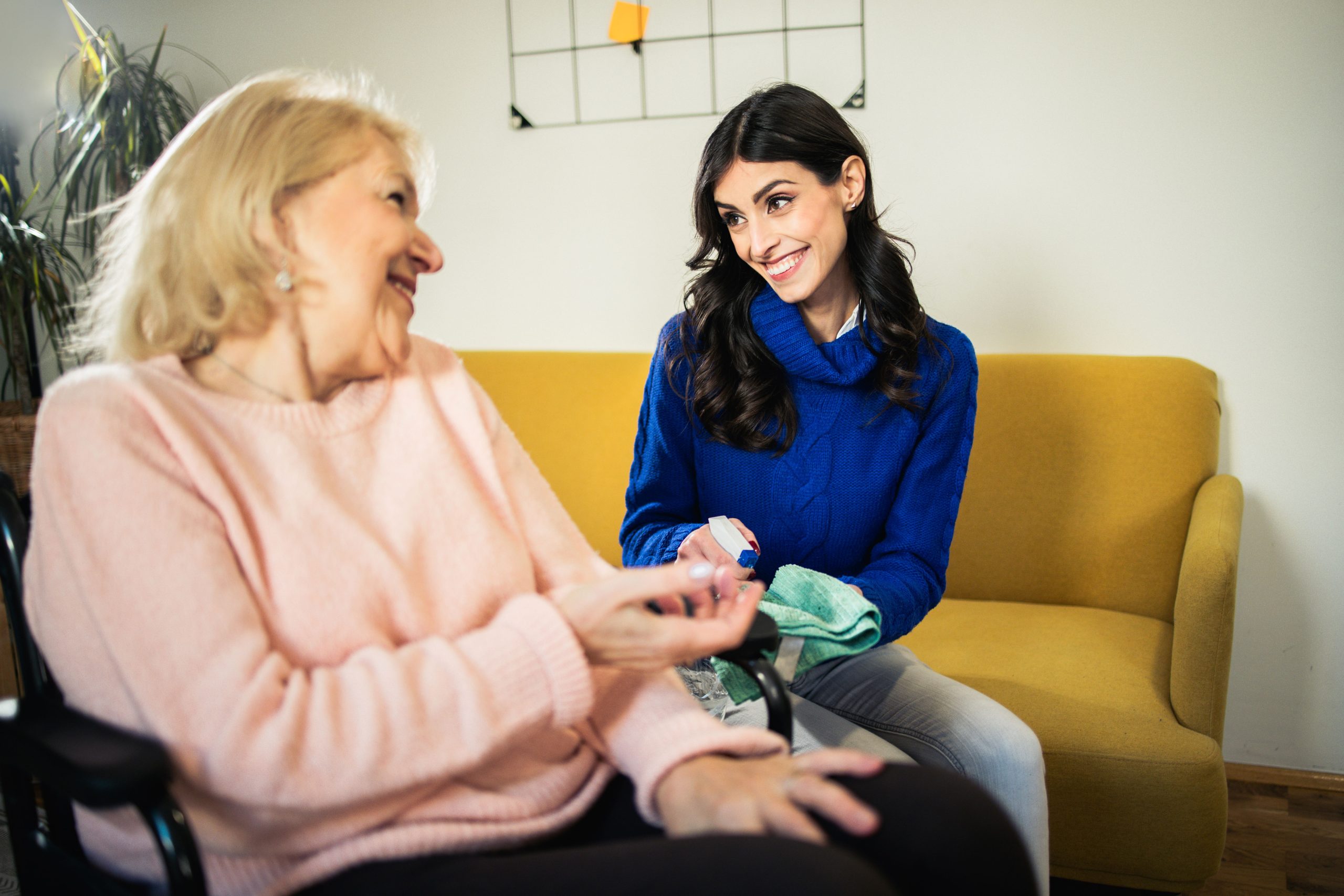 An older woman chats with her granddaughter while she cleans the house.