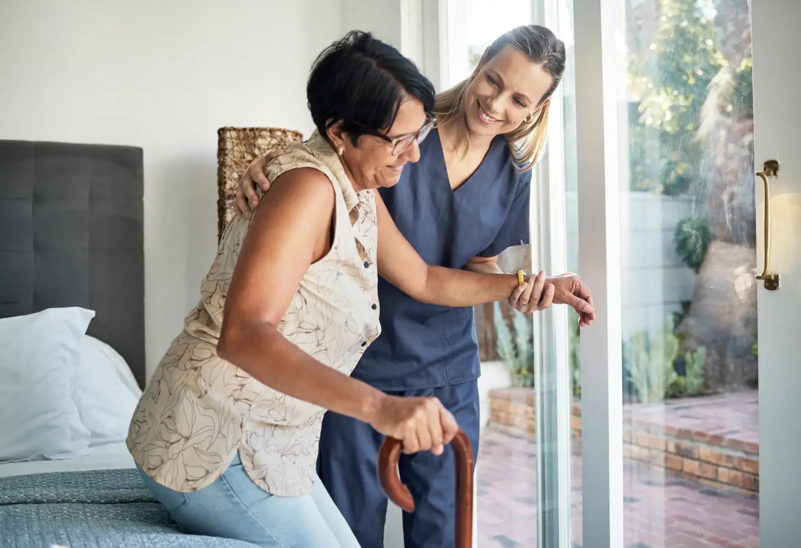 SYNERGY HomeCare caregiver helping senior get out of bed.