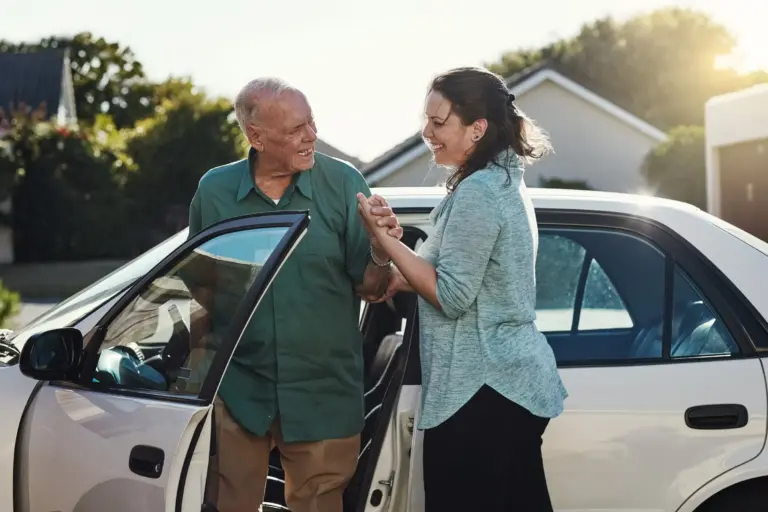 A SYNERGY HomeCare caregiver assists a senior in getting out of the car following an appointment.