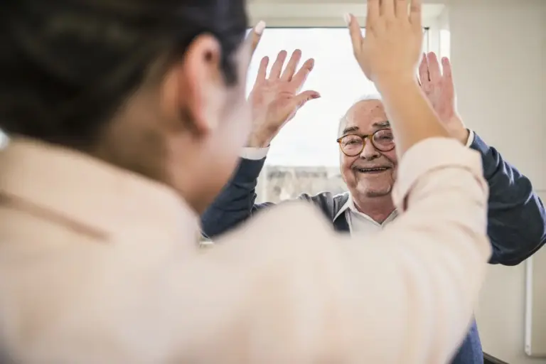 Older man high fives his family caregiver.