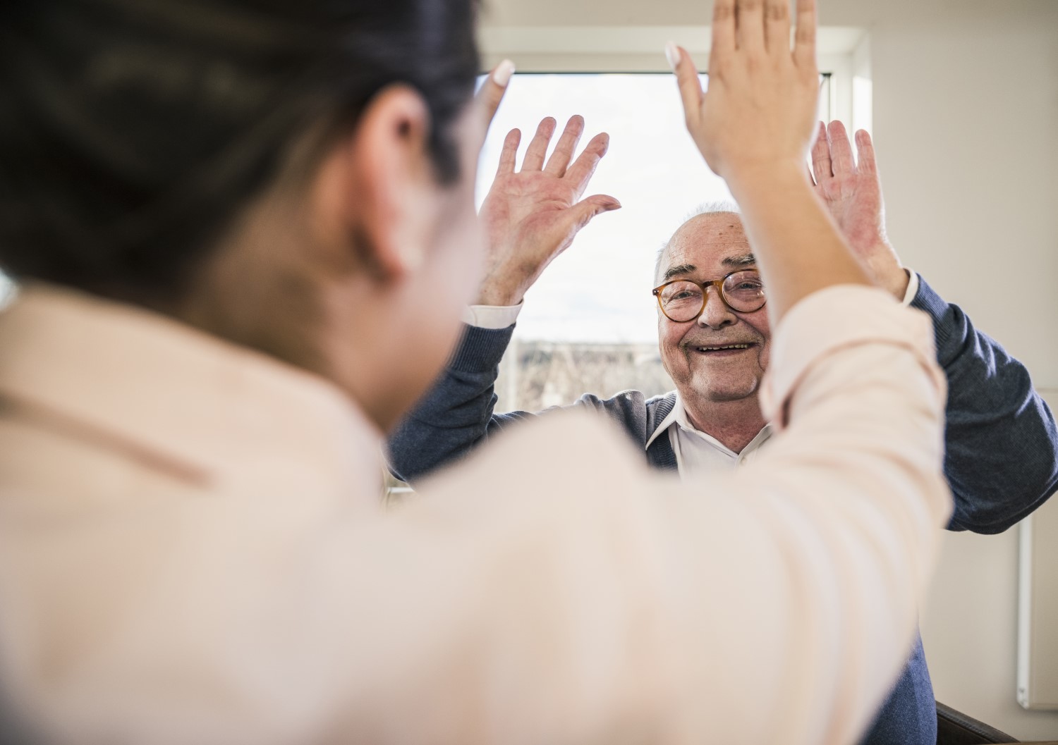 Older man high fives his family caregiver.