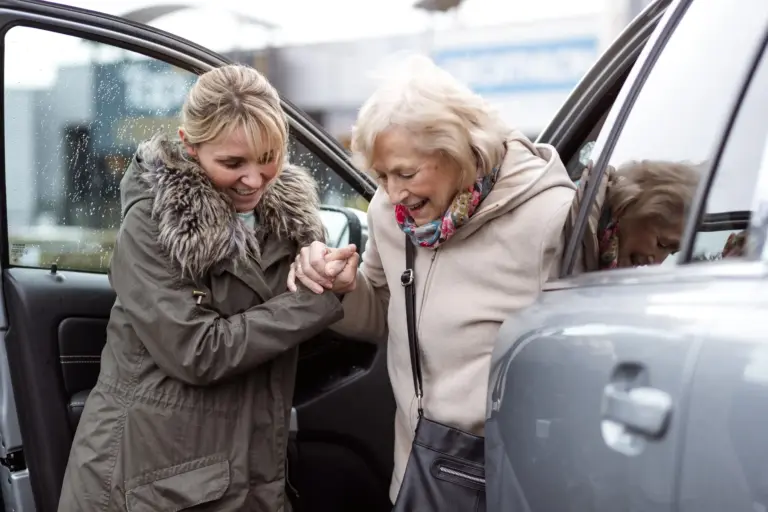 SYNERGY HomeCare caregiver helps senior out of car.