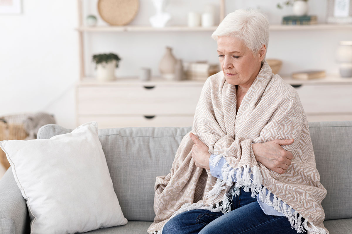 grandma on couch with blanket around her shoulders looking cold