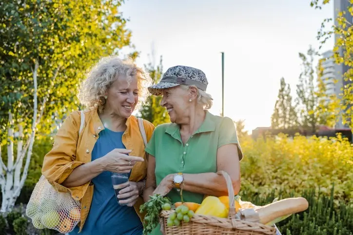 Two older women walk around their community after shopping for healthy and fresh foods for Active Aging week.