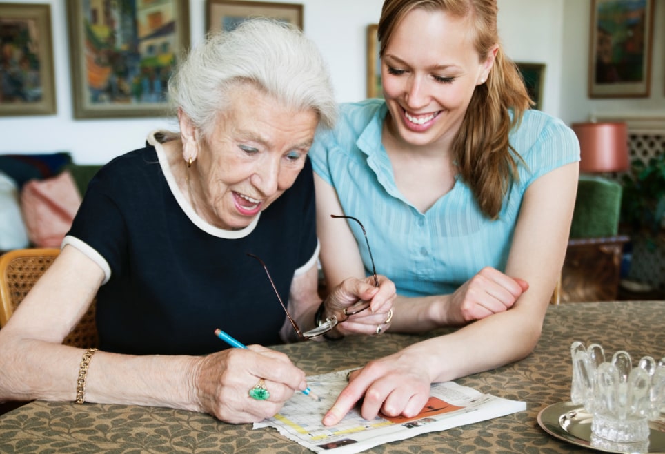 woman and senior woman enjoying doing a crossword puzzle together