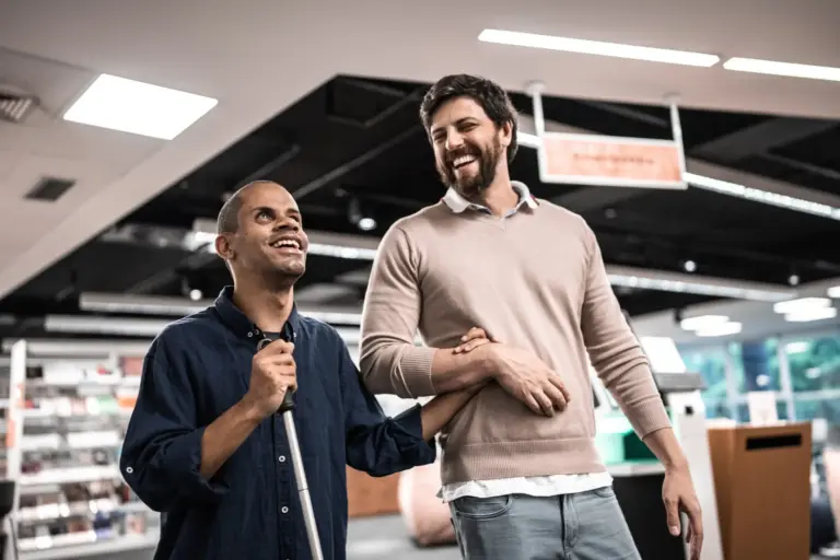 Middle-aged adult man who is visually impaired talking and smiling with friend