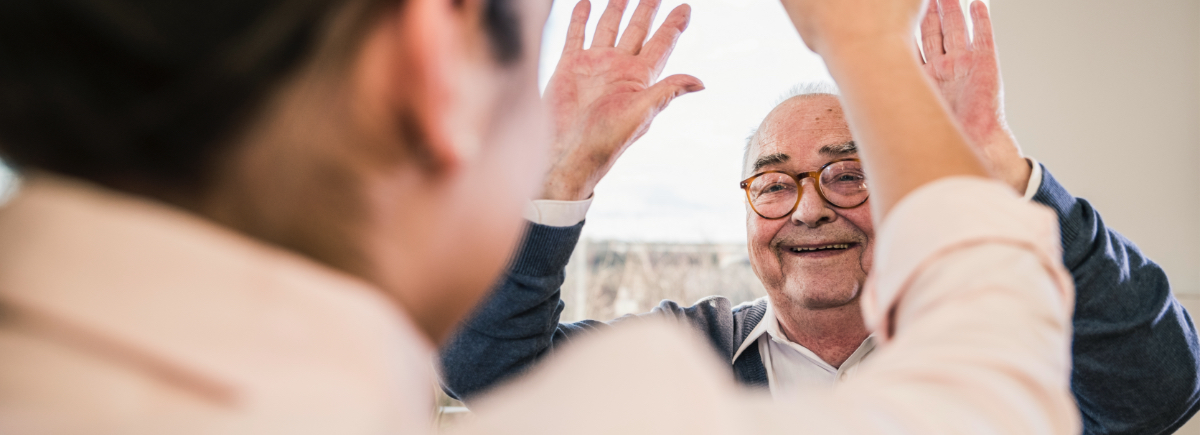 over the shoulder of two senior men giving each other high fives