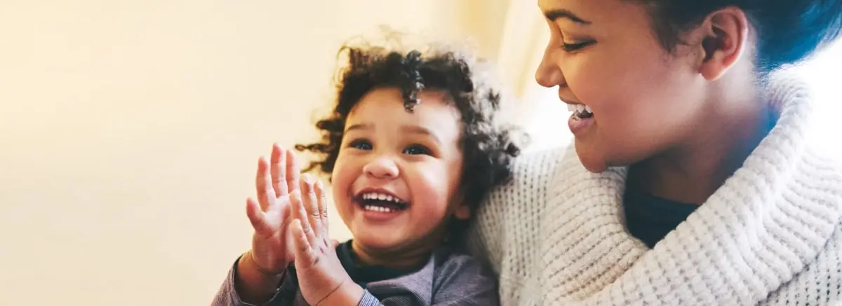 Mother holding her young toddler and happy because they found a home care agency near them that can help watch him.