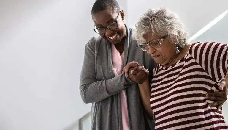 SYNERGY HomeCare caregiver helping client down stairs