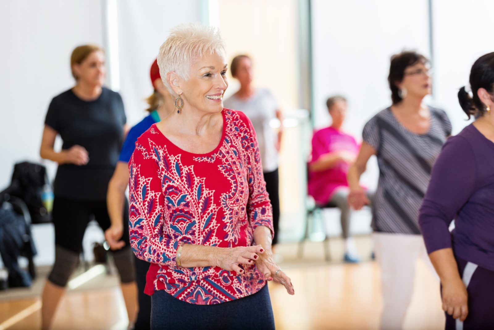 Joyful seniors enjoying a dance activity at a senior benefits center