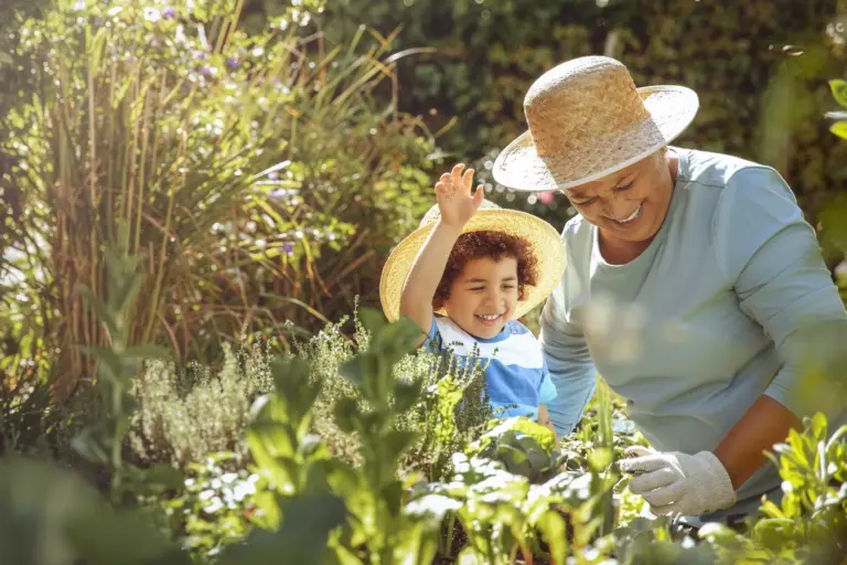 Grandmother and grandson in a sunny garden with hats and shade — summer safety for seniors.