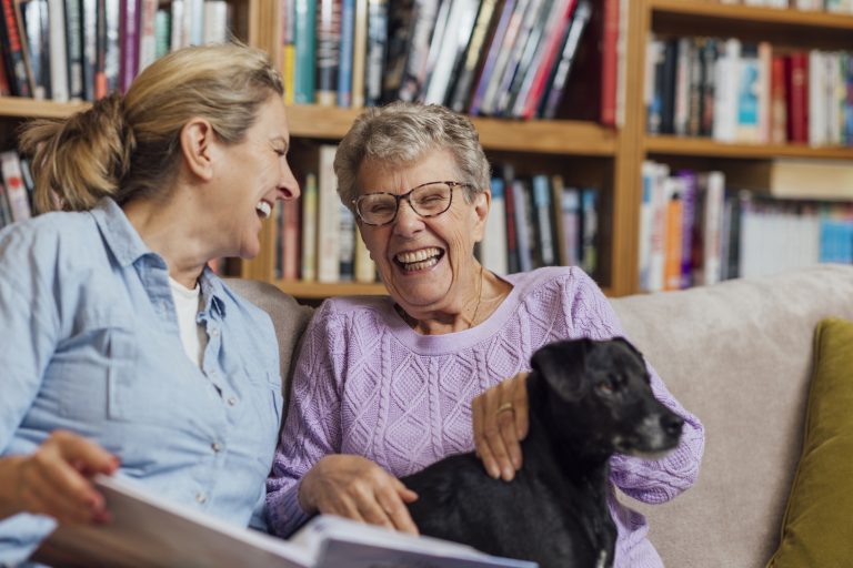At-home companionship: daughter and senior mother sharing a photo album — aging in place with in-home support