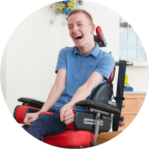 Young disabled man in a wheelchair laughing while spending time with his caregiver from SYNERGY HomeCare of Rutherford County.