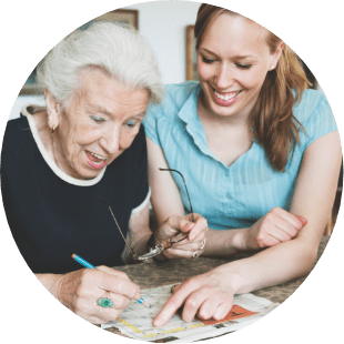woman and senior woman enjoying doing a crossword puzzle together