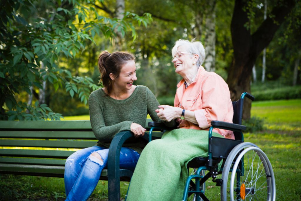 Senior woman in a wheelchair out at a park in Murfreesboro, TN accompanied by her caregiver from SYNERGY HomeCare of Rutherford County.