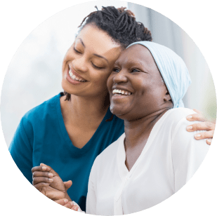 A woman recovering from an illness at her home in Charleston, SC thanks for the help from the SYNERGY HomeCare caregiver that is hugging her and smiling with her.