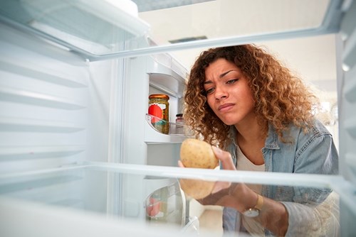 adult child looking in parent's empty refrigerator