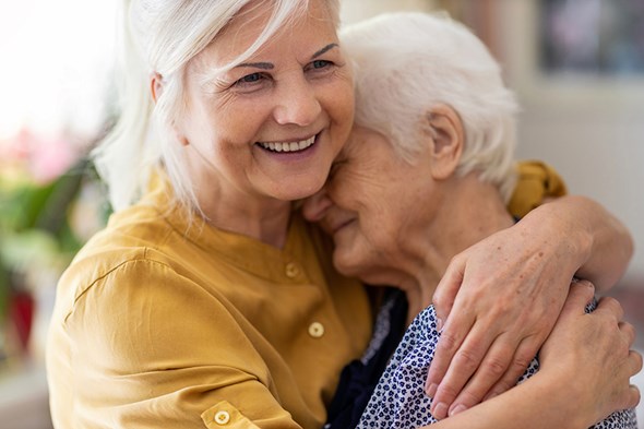 adult daught hugging aging mother smiling
