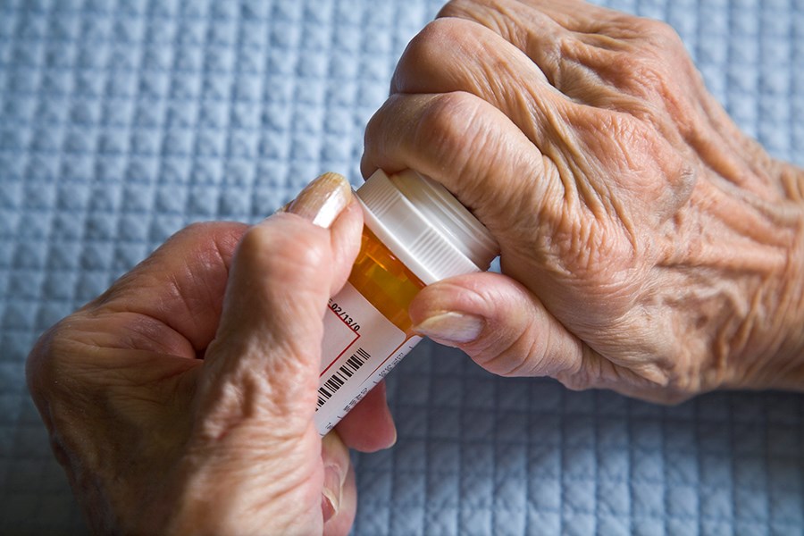 arthritic senior's hands opening prescription bottle