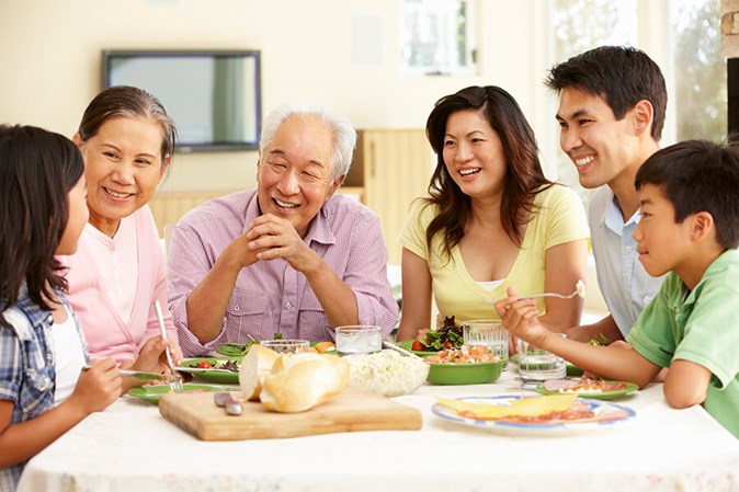 three generations of family at dinner table-grandparents and their kids and grandkids