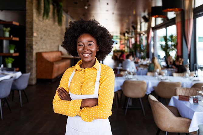black restaurant server femail with apron on and smiling