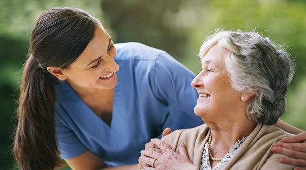 female caregiver tlking to senior woman with short grey hair