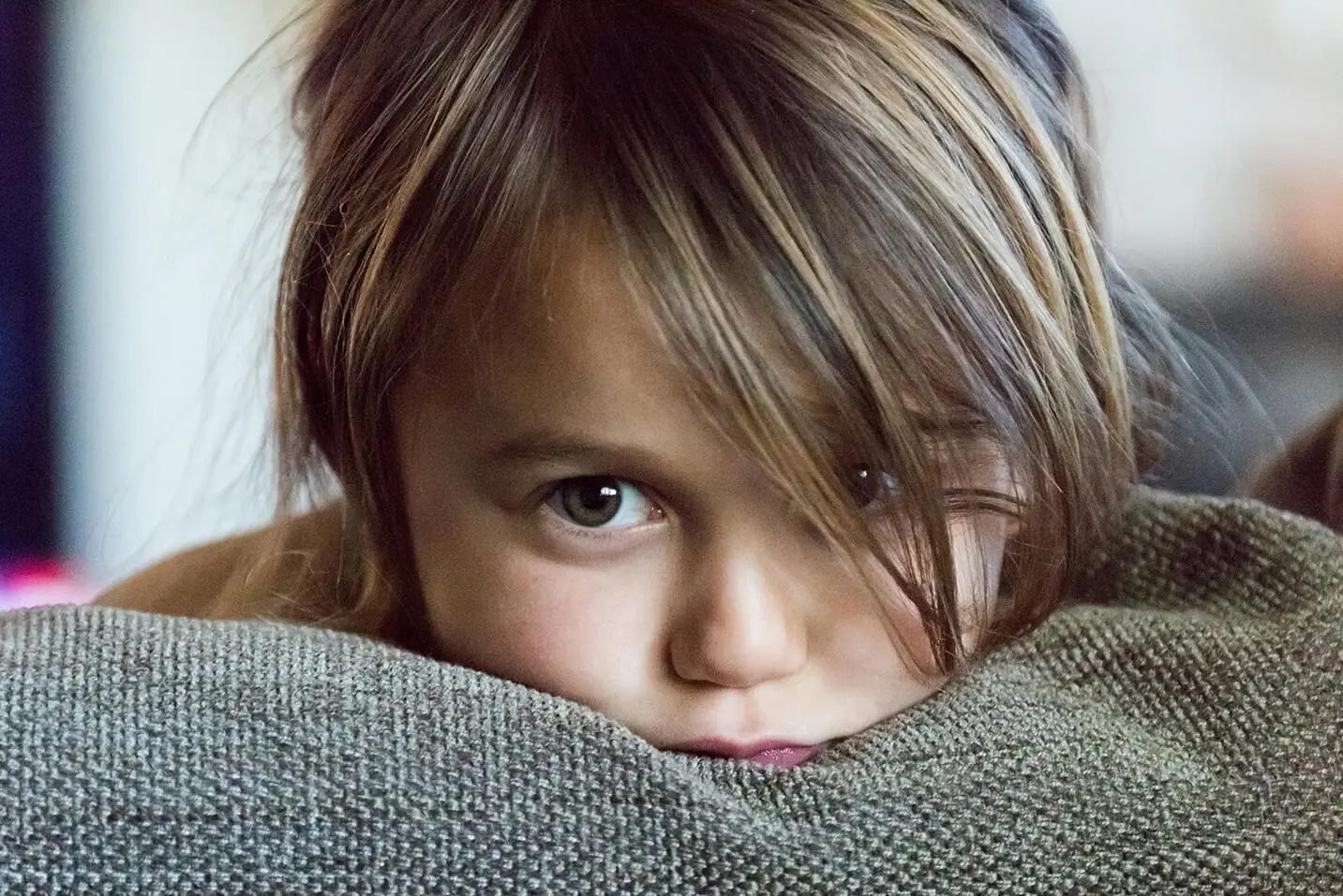 young girl with chin on pillow staring with big brown eyes