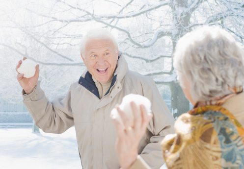 Couple Throwing Snowballs Feeling The Holiday Spirit