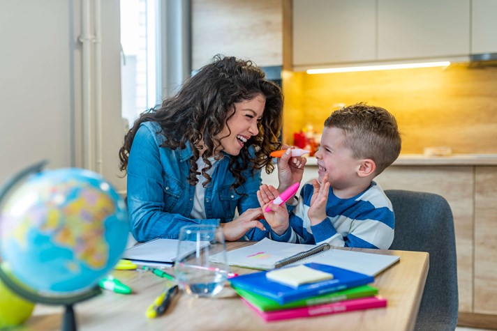caregiver help young boy do his homework at home