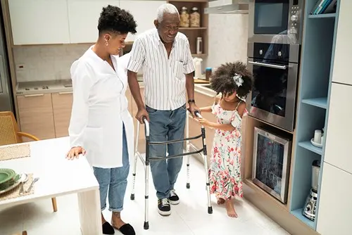 family assisting senior relative with walker in home