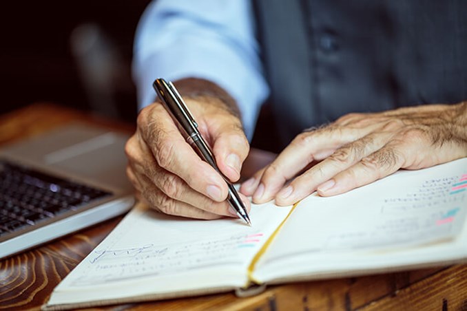 senior man hands with pen writing in journal