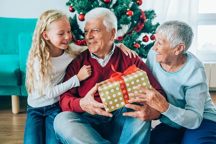 grandma and grandpa getting gift from granddaughter