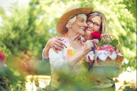 happy senior and caregiver picking flowers