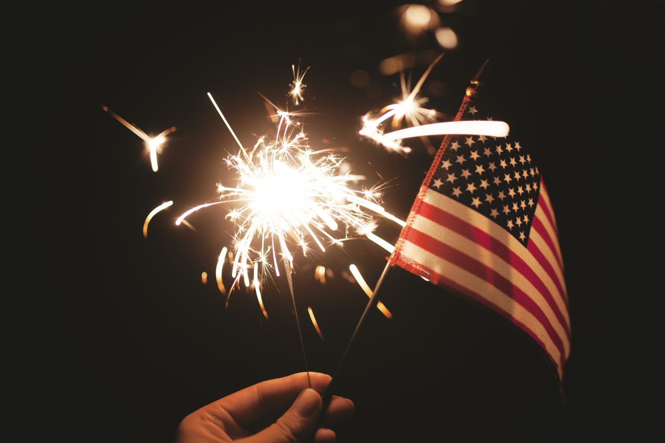 A person hold an American flag and sparkler